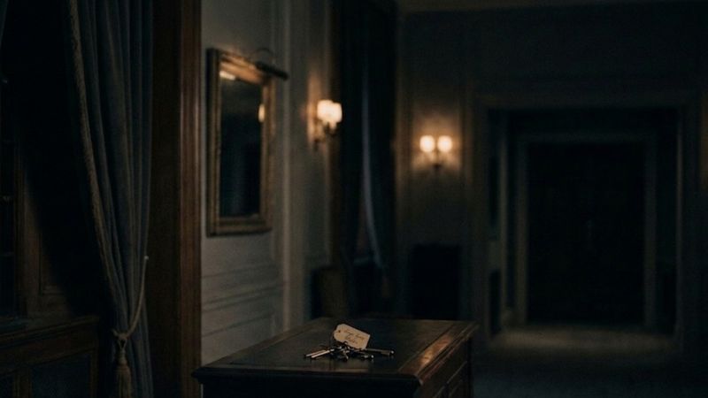 Dimly lit hallway with keys on a wooden table creating a mysterious atmosphere.