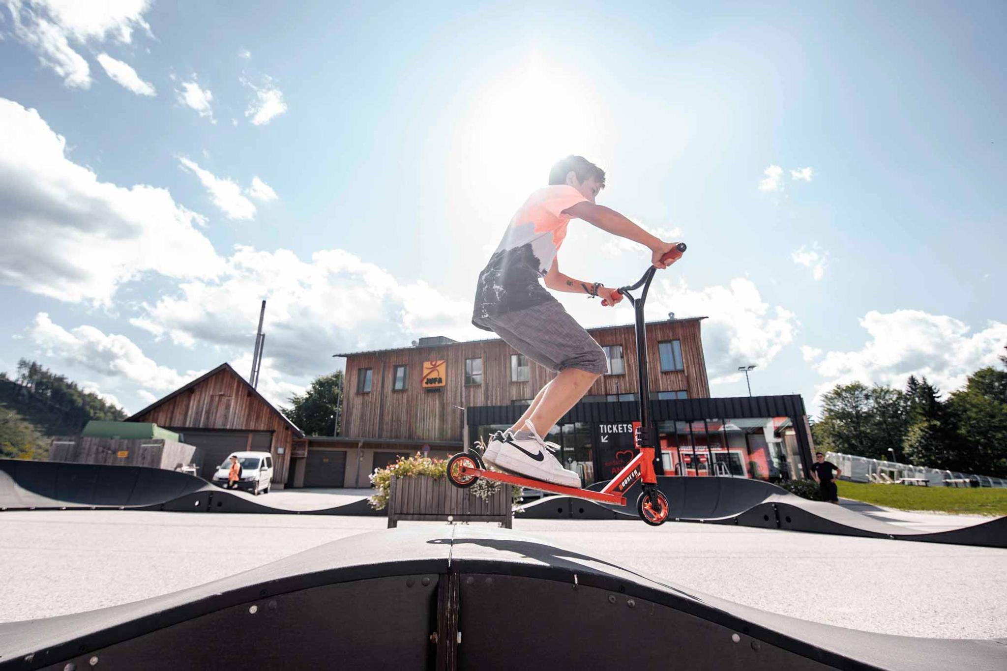 Ein Kind fährt mit seinem Scooter den Pumptrack entlang