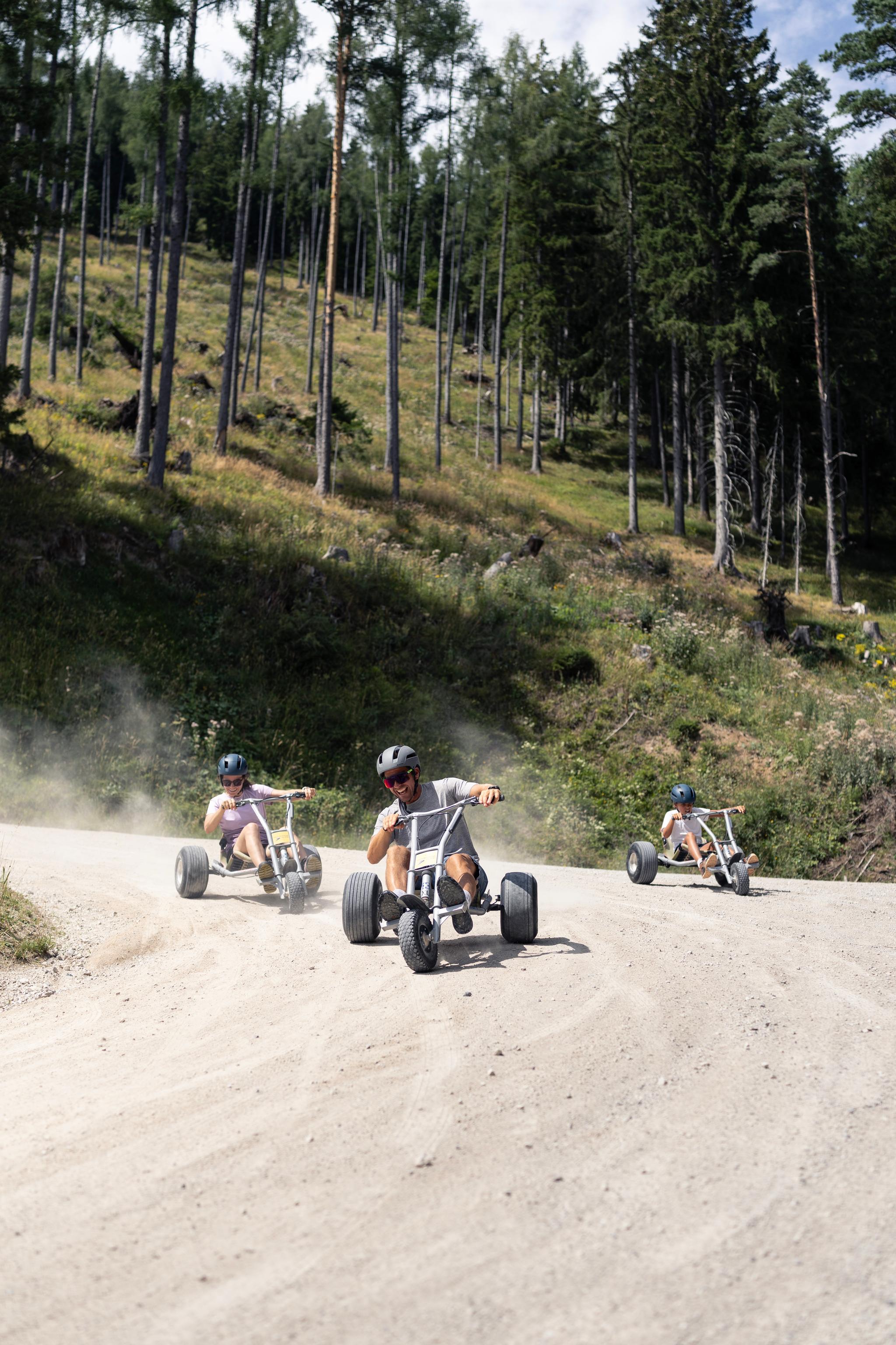 Eine Gruppe von Freunden fährt mit den Mountaincarts über die Schotterstraße hinunter