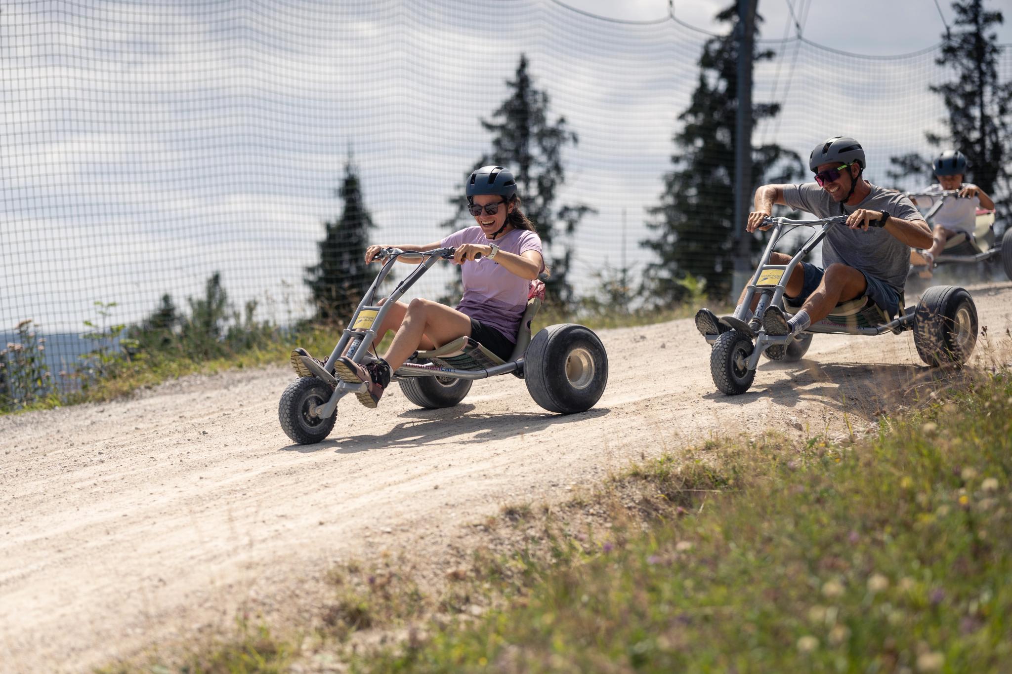 2 Personen düsen mit dem Mountaincart den Berg hinab
