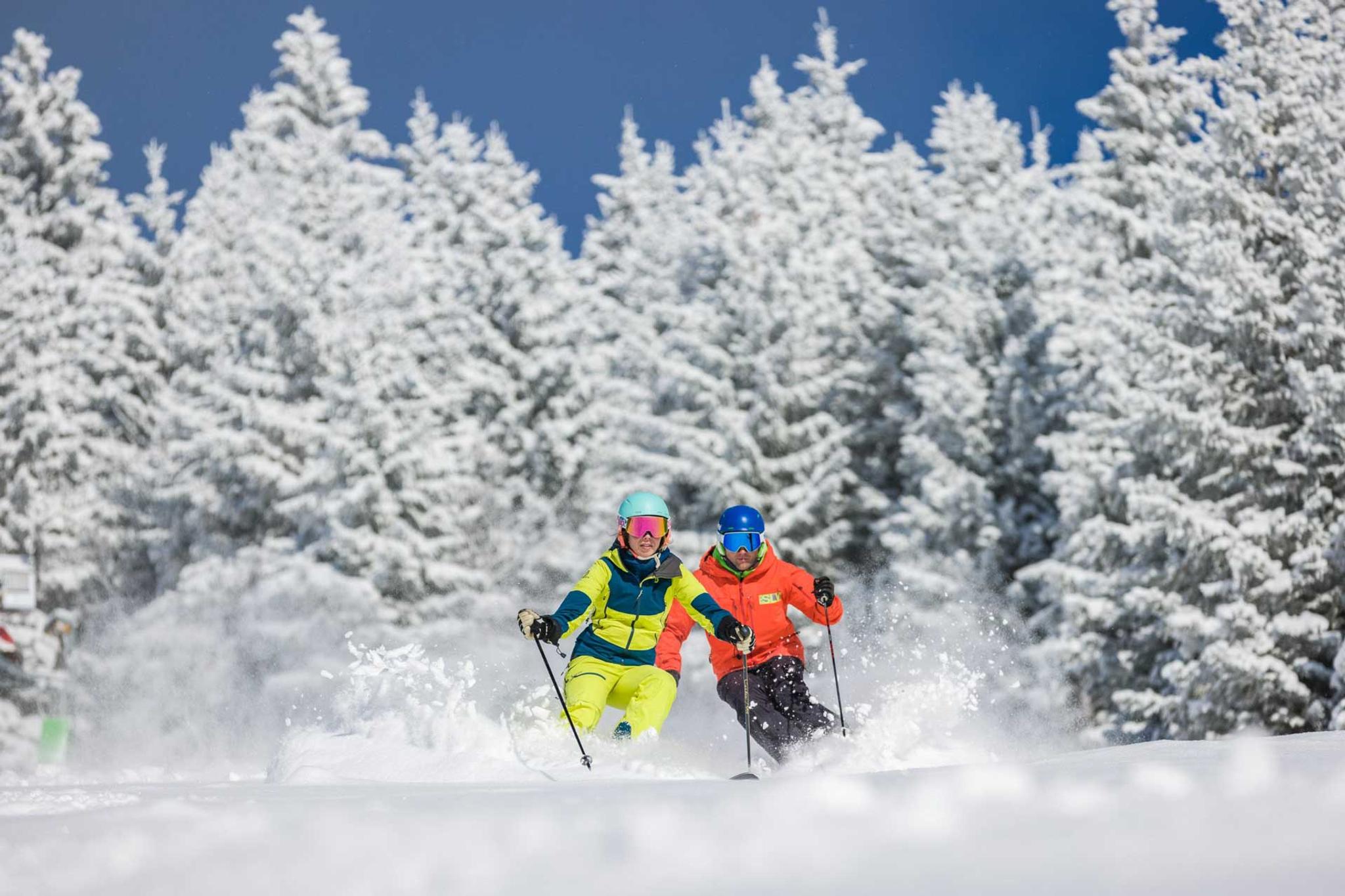 2 SchifahrerInnen düsen bei Neuschnee die Pisten hinab