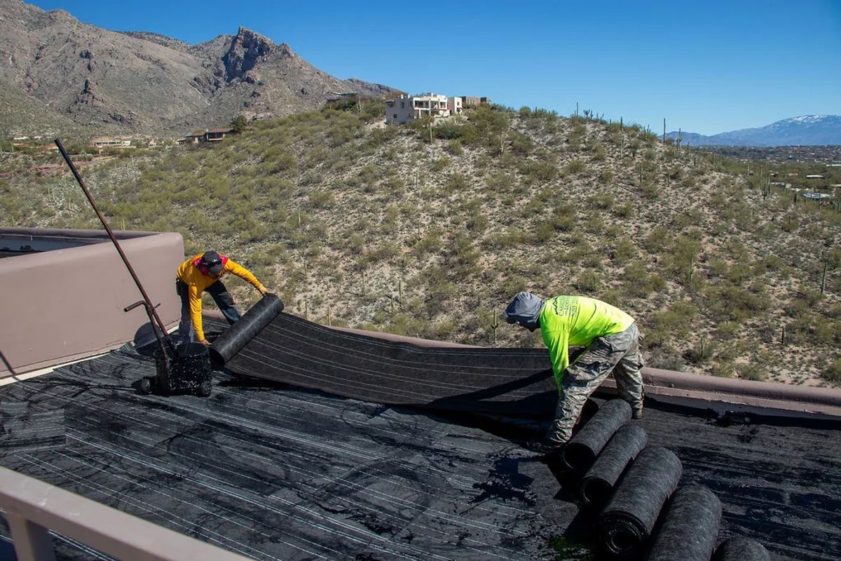 Crew installing a flat roof, mountains in the distance