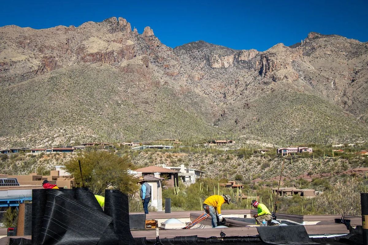 Camelback Roofing crew re-roofing a desert home with mountains behind