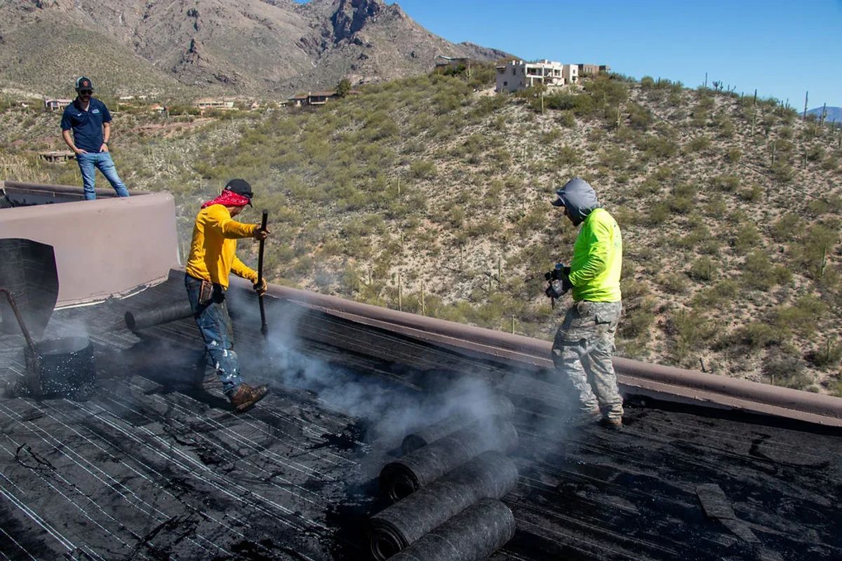 Roofer working modified bitumen on a flat roof edge