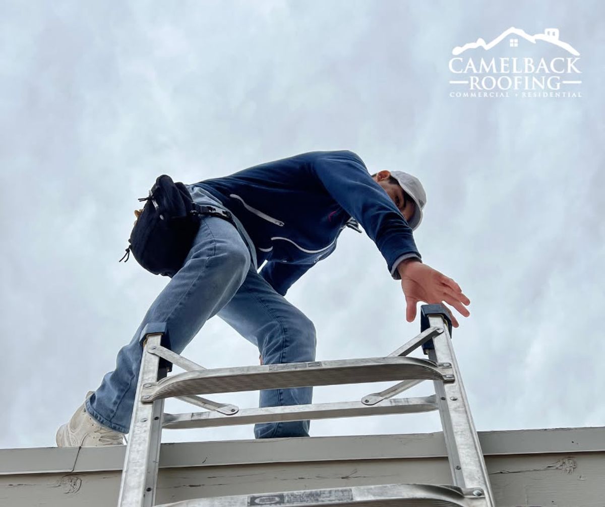 Camelback Roofing technician climbing a ladder to inspect a roof