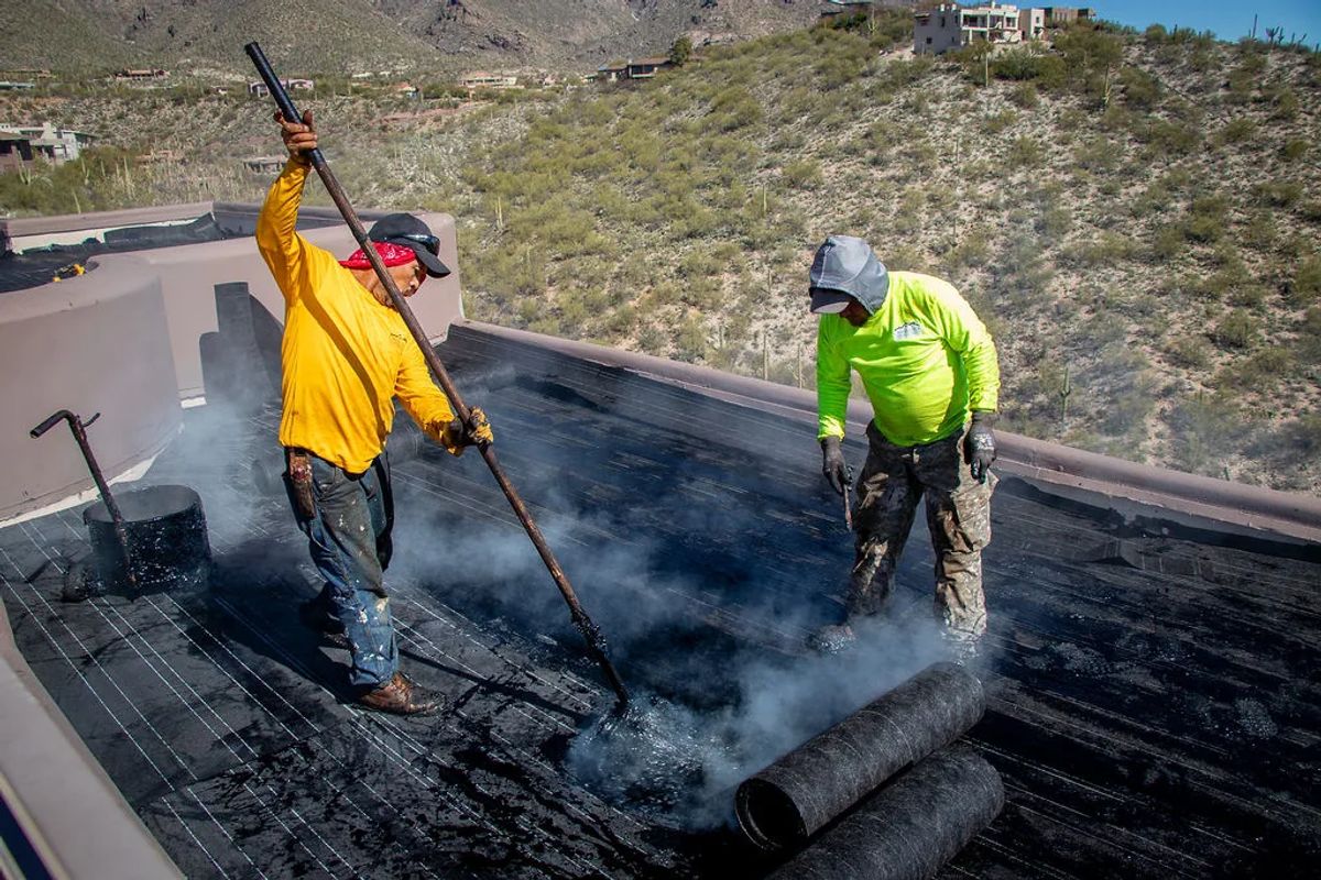 Two roofers working a flat roof with mountain views