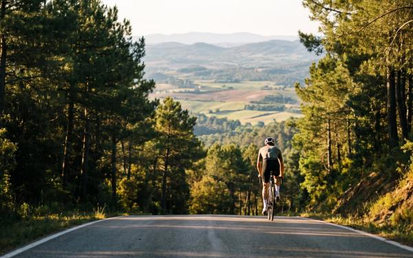A lone road cyclist climbing a steep, quiet mountain road on Rocacorba near Girona