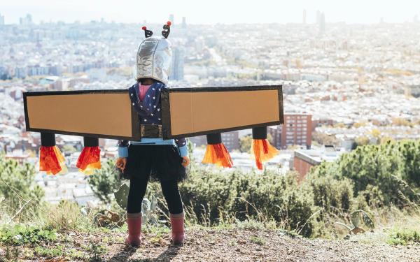 Young adventurous girl with fake wings made of cardboard