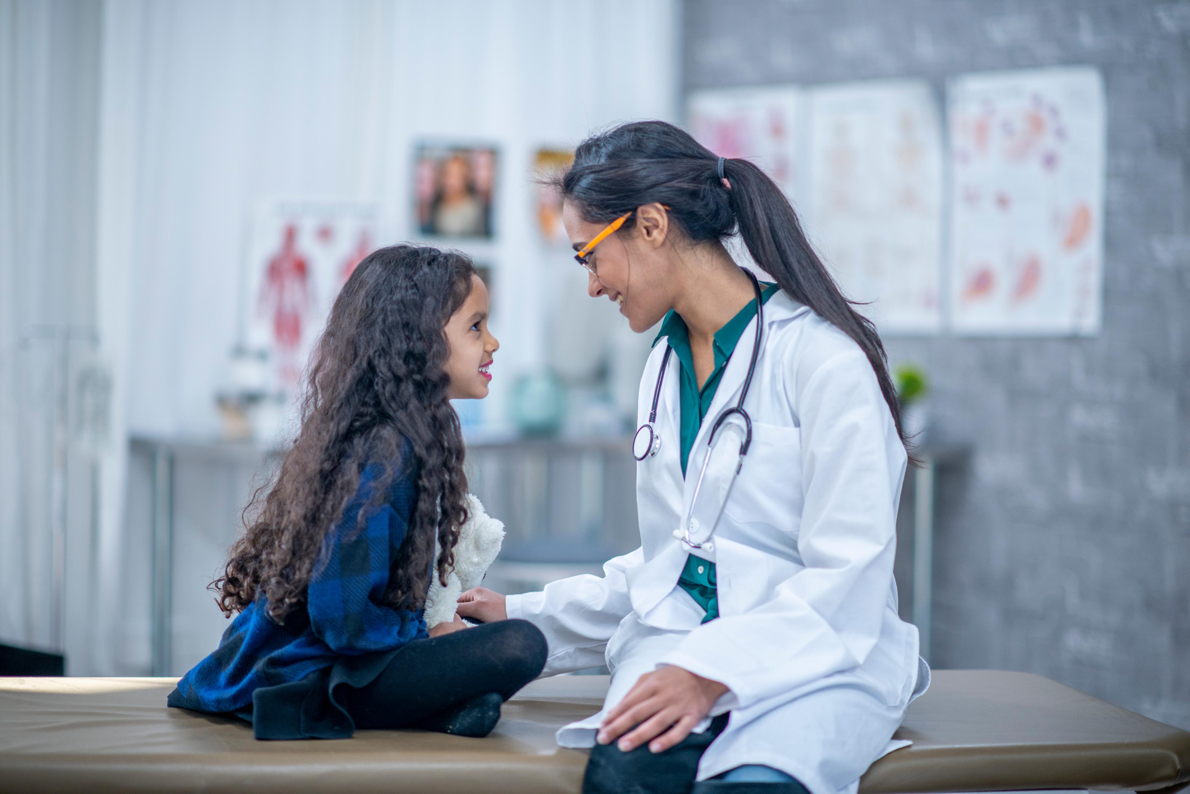 Is an FNP degree worth it? a picture of an FNP smiling with a young female patient