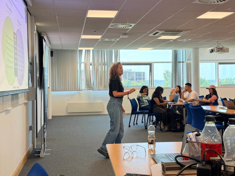 AI Lab facilitator presenting to a small group of participants in a bright modern conference room with panoramic city and waterfront views