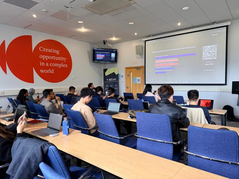MBA students working on laptops during the Agentic AI Lab session, AI Lab banner and 'Our purpose is to make a positive impact' wall visible, Leeds University Business School, 12 June 2026