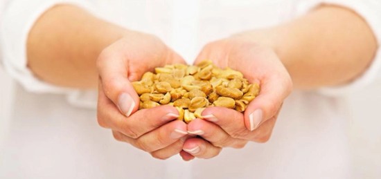 a person holding a handful of peanuts in their hands.