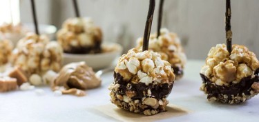 bite-sized popcorn lollipops dipped in chocolate and diced peanuts.