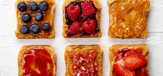 A variety of toasts with jam and berries on them.