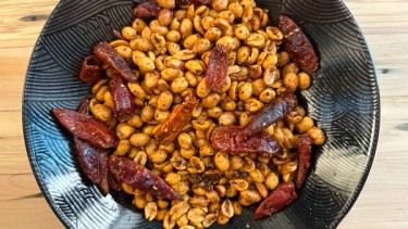 peanuts with seasoning and chilis in a black bowl