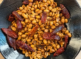 peanuts with seasoning and chilis in a black bowl