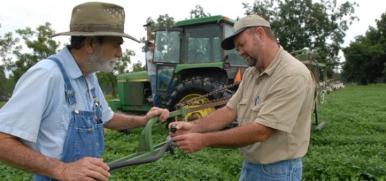 two farmers operating a machine in a field.