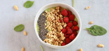 a bowl filled with granola, raspberries and chia seeds.