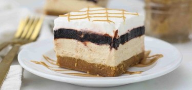 a four layered cake with a thick cheesecake part in the middle topped with chocolate pudding.