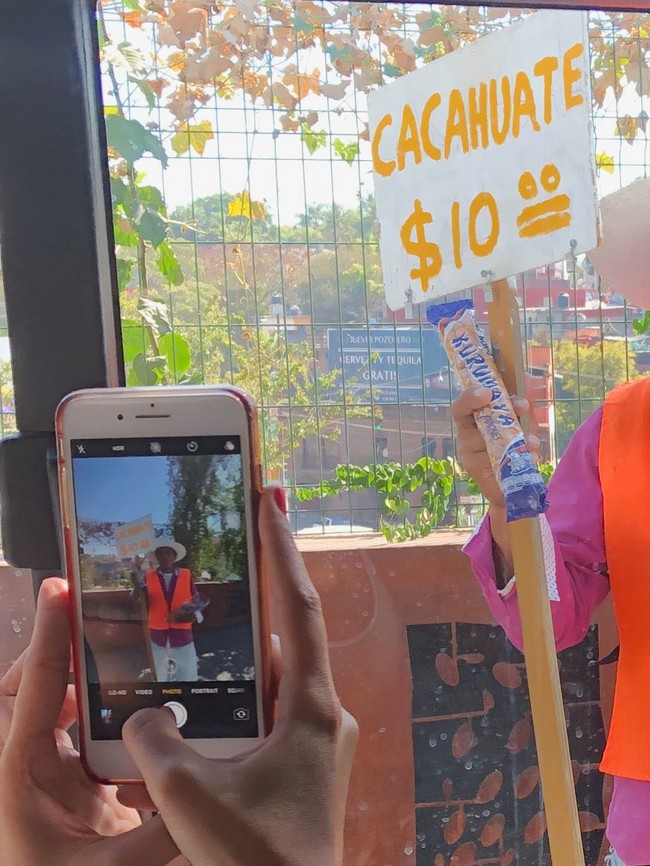 a mexican street vendor holding a plaque that says cacahuate $10