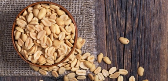 a wooden bowl filled with peanuts on top of a table.