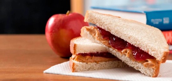 A PB&J sandwich next to an apple.