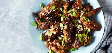 grilled chicken wings covered in peanuts and scalions.