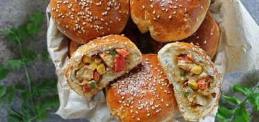 a paper bag full of buns filled with chicken and vegetables.