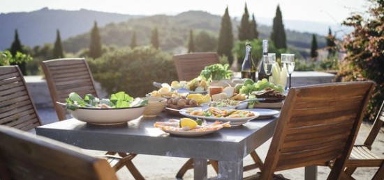 A table set with food and wine on a patio.