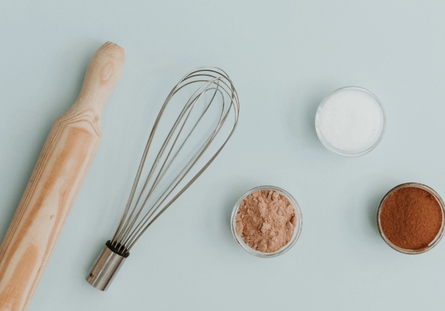 a whisk, rolling pin and small bows on a table