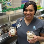 woman holding two cups of dessert made with peanuts
