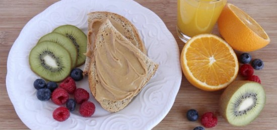 a plate of toasts with peanut butter, fruits and a glass of orange juice.