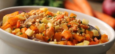 a bowl full of chopped vegetables sprinkled with diced peanuts.