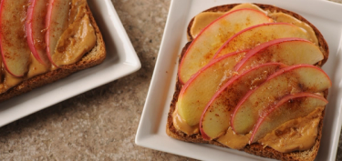 a peanut butter sandwich with sliced apples on top.