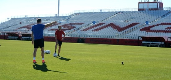 Two man playing soccer on a empty stadium.