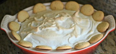 a pudding with baked frosting topped with cookies on the sides.