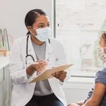 A woman doctor is giving instructions to a kid next to her mother.