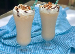 two glasses of milkshakes on a blue and white checkered cloth.