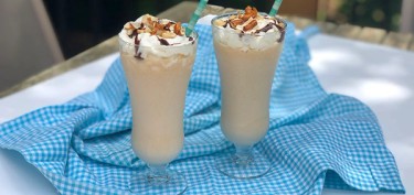 two glasses of milkshakes on a blue and white checkered cloth.
