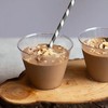 two small glasses of chocolate smoothie topped with banana slices.