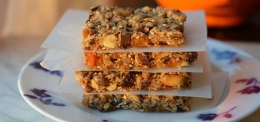 a stack of four granola bars made of nuts and dried fruits.