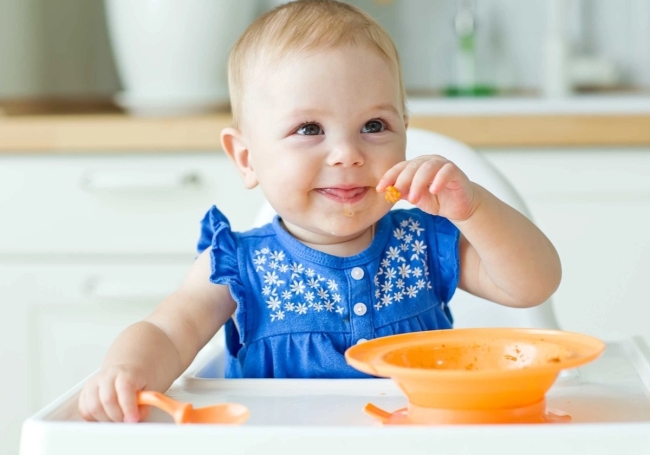 happy baby eating from a small bowl