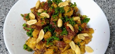 plate of cooked sweet potatoes topped with peanuts and chopped cilantro.