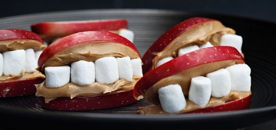 Apple slices covered in peanut butter and filled with marshmallow to look like teeth.