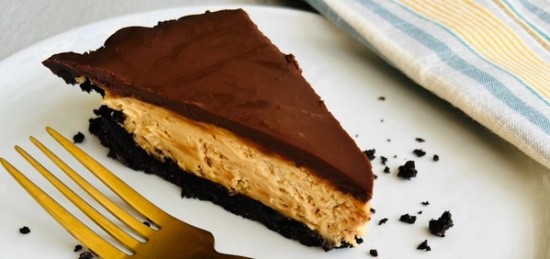 A slice of peanut butter pie topped with a thick layer of chocolate.