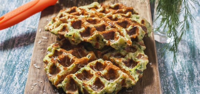 two waffles made of shredded veggies drizzled in maple syrup.