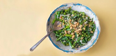 a bowl full of peanuts, green beans and chopped asparagus.