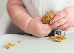 a baby holding a sweet dough in their hands.