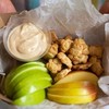 a paper box full of apple slices, kids crackers and a dip sauce.