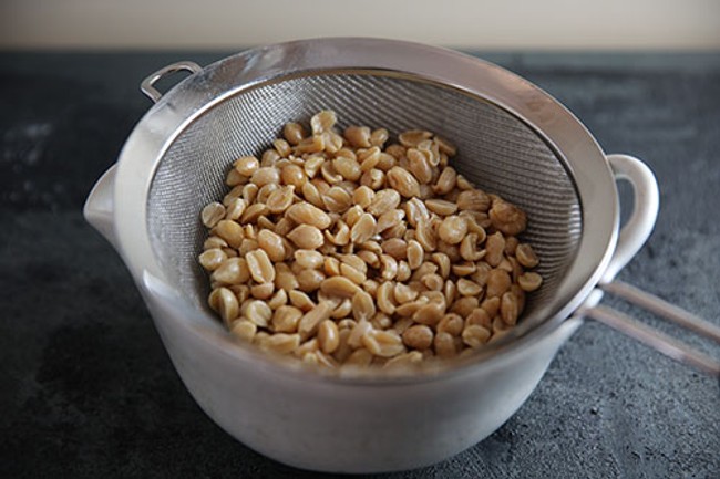 a sieve filled with peanuts on top of a cup